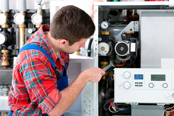 Heating technician repairing boiler controls in Selma