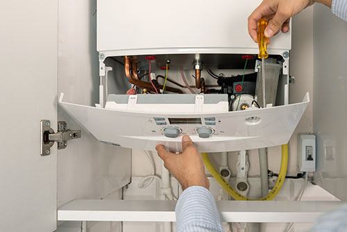 Heating technician repairing a residential boiler in Selma