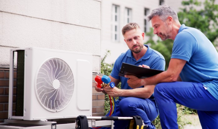 HVAC technicians installing an outdoor air conditioning unit in Selma
