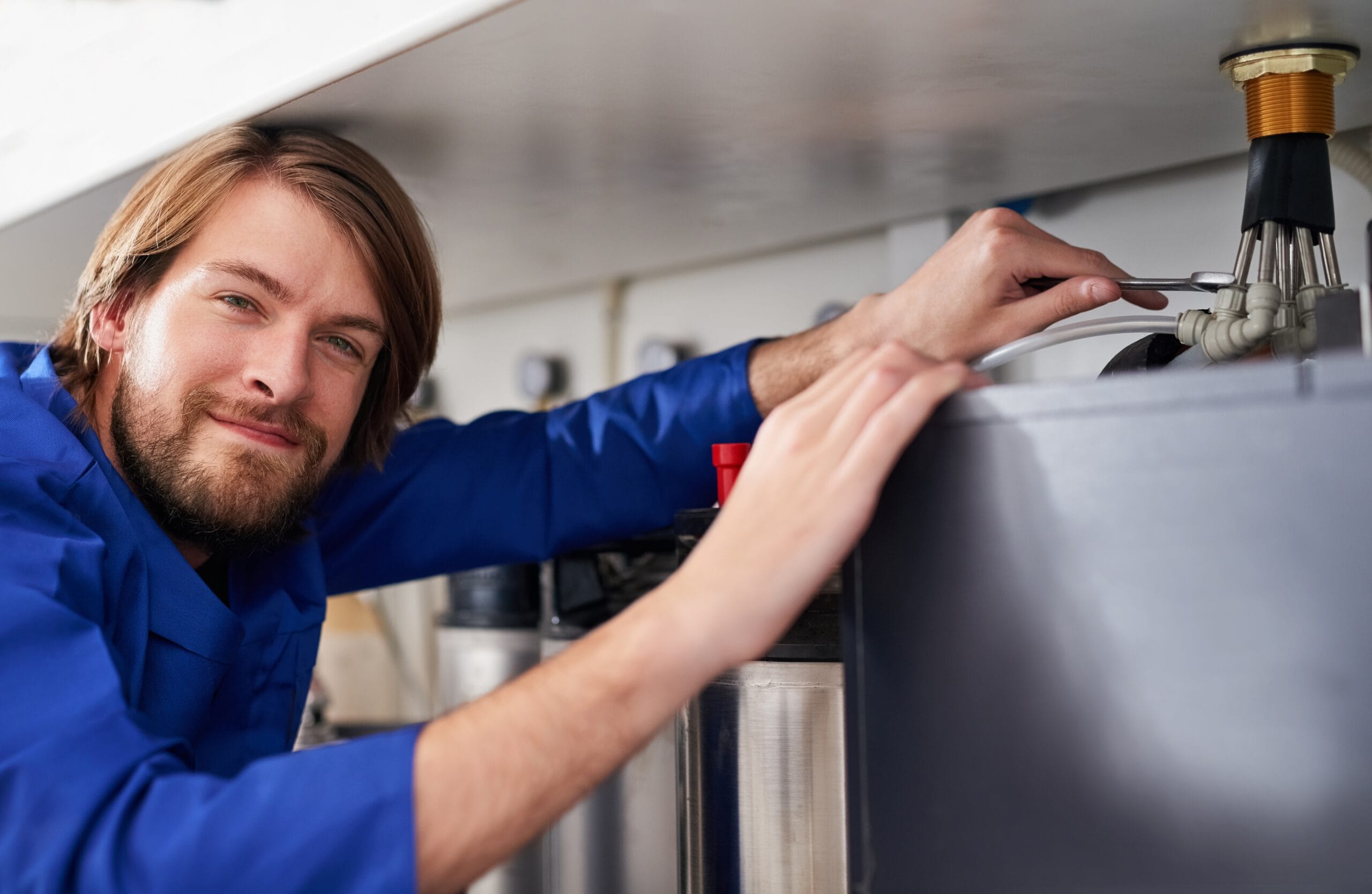Technician servicing a residential water heater tank in Selma